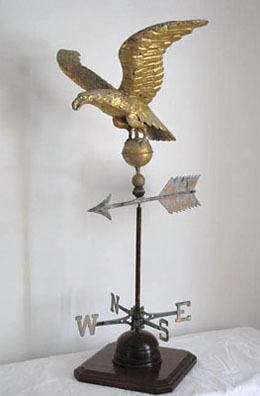 Great Eagle Weathervane in its original gold gilt paint, standing on a ball with pointing arrow, mounted on a custom wooden stand.